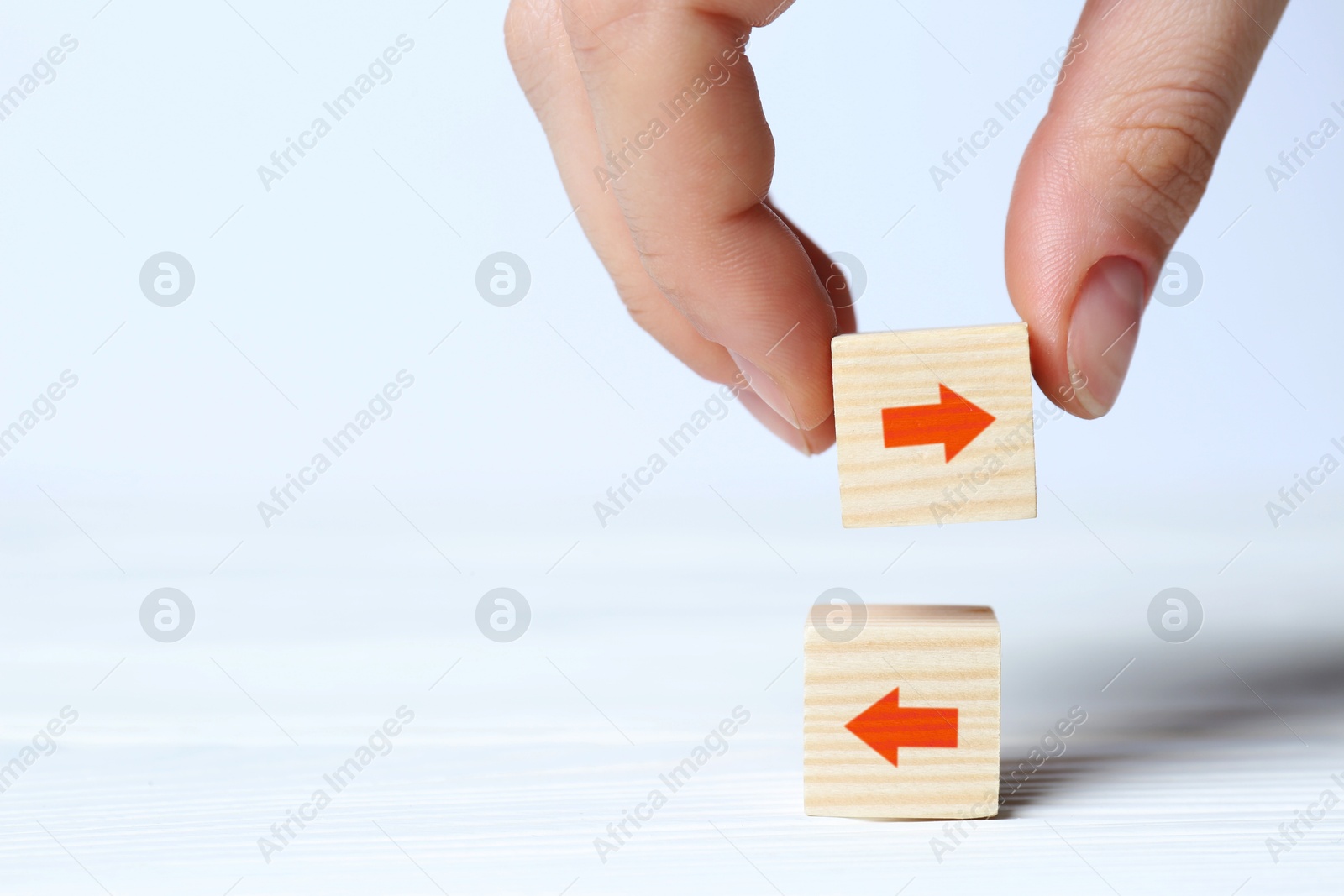 Image of Woman holding wooden cube with red arrow on white background, closeup. Space for text