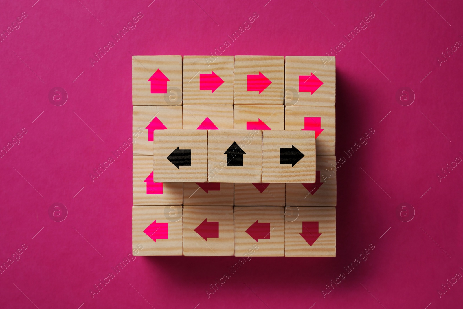 Image of Wooden cubes with arrows on dark pink background, top view