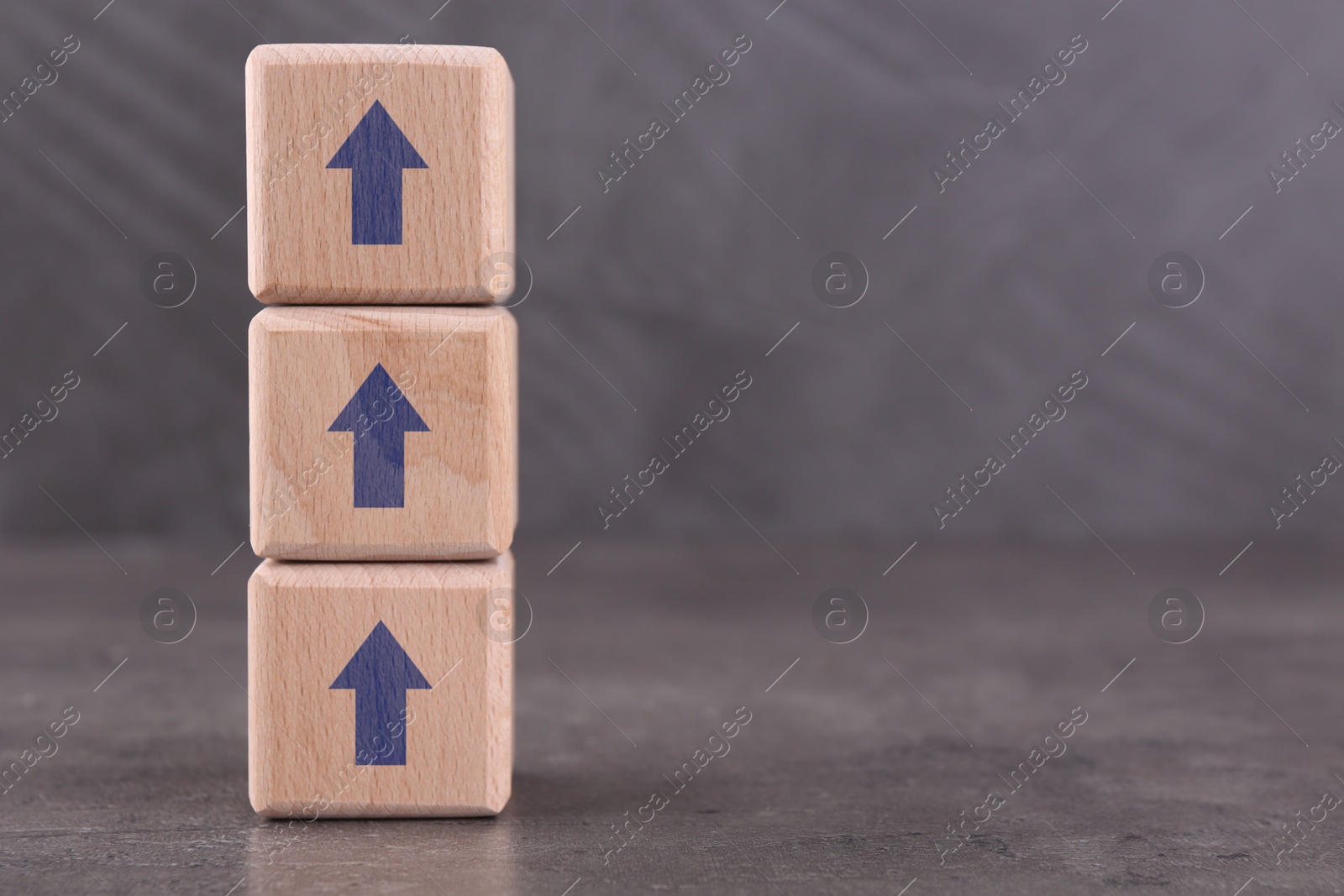 Image of Wooden cubes with blue arrows on grey table, space for text