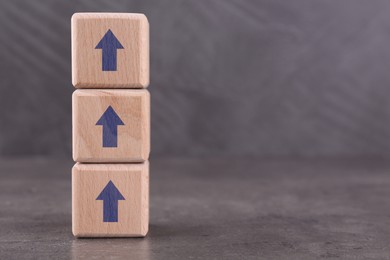 Image of Wooden cubes with blue arrows on grey table, space for text