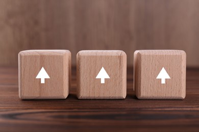 Image of Cubes with white arrows on wooden table, closeup