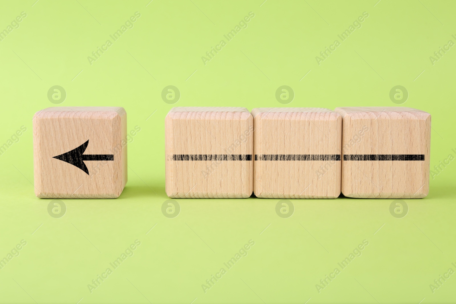 Image of Arrow made of wooden cubes on light green background