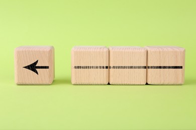 Image of Arrow made of wooden cubes on light green background