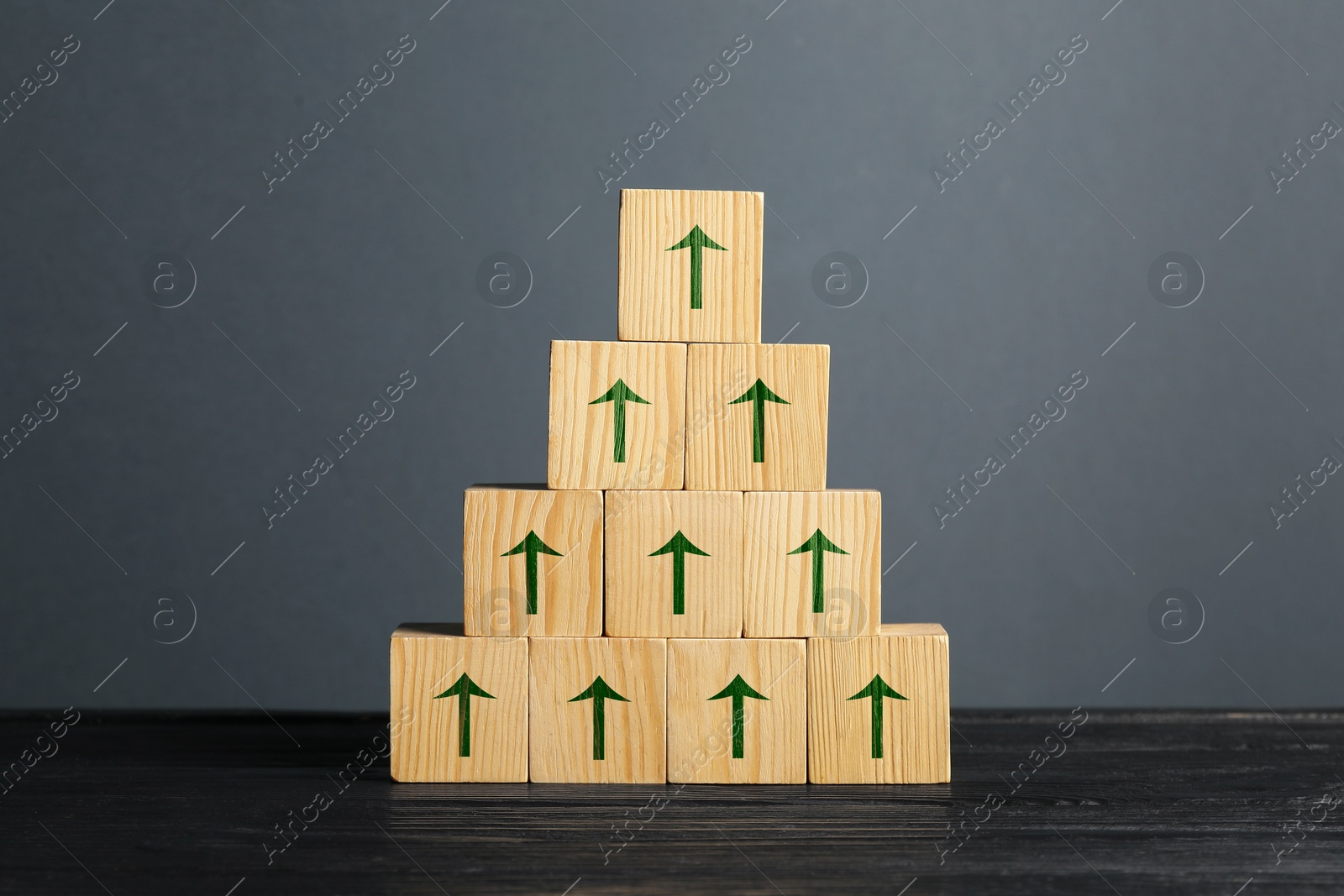 Image of Cubes with green arrows on black wooden table against grey background