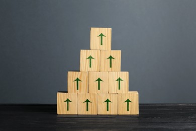 Image of Cubes with green arrows on black wooden table against grey background