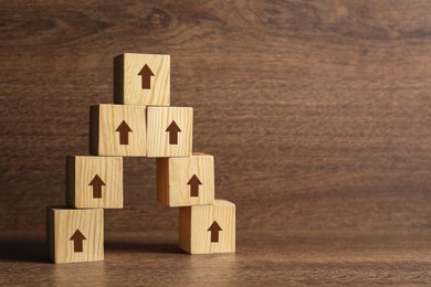 Image of Cubes with arrows on wooden table, space for text