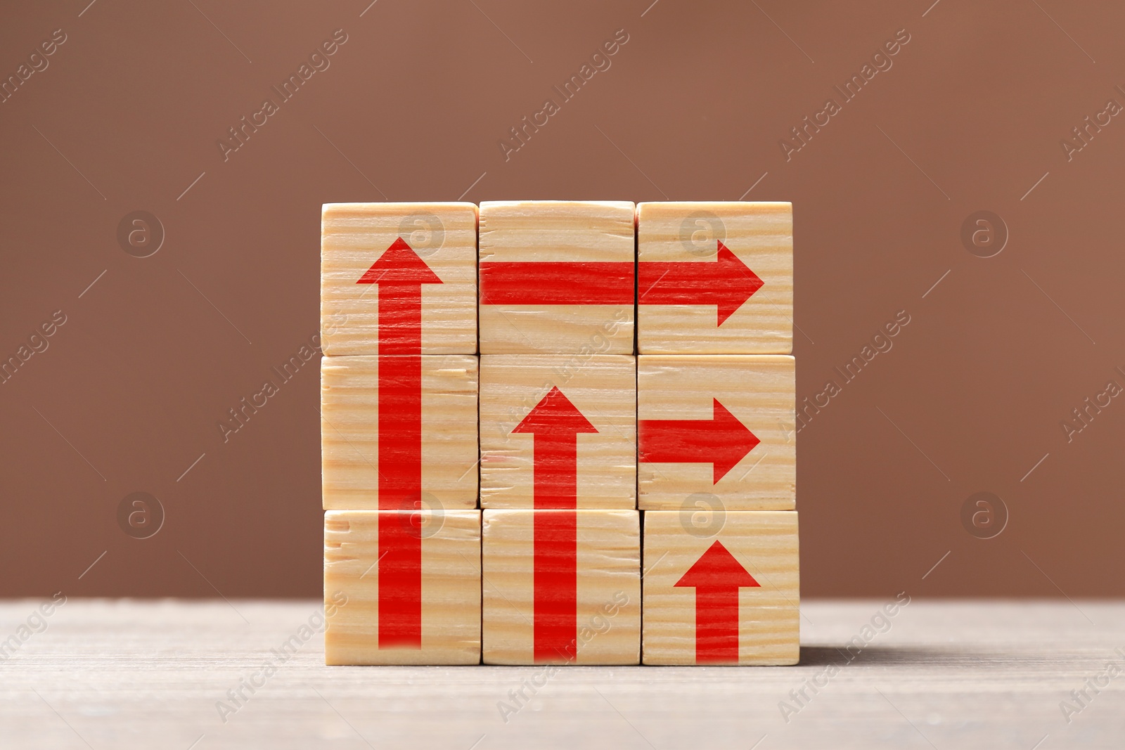 Image of Wooden cubes with red arrows on table against pale brown background