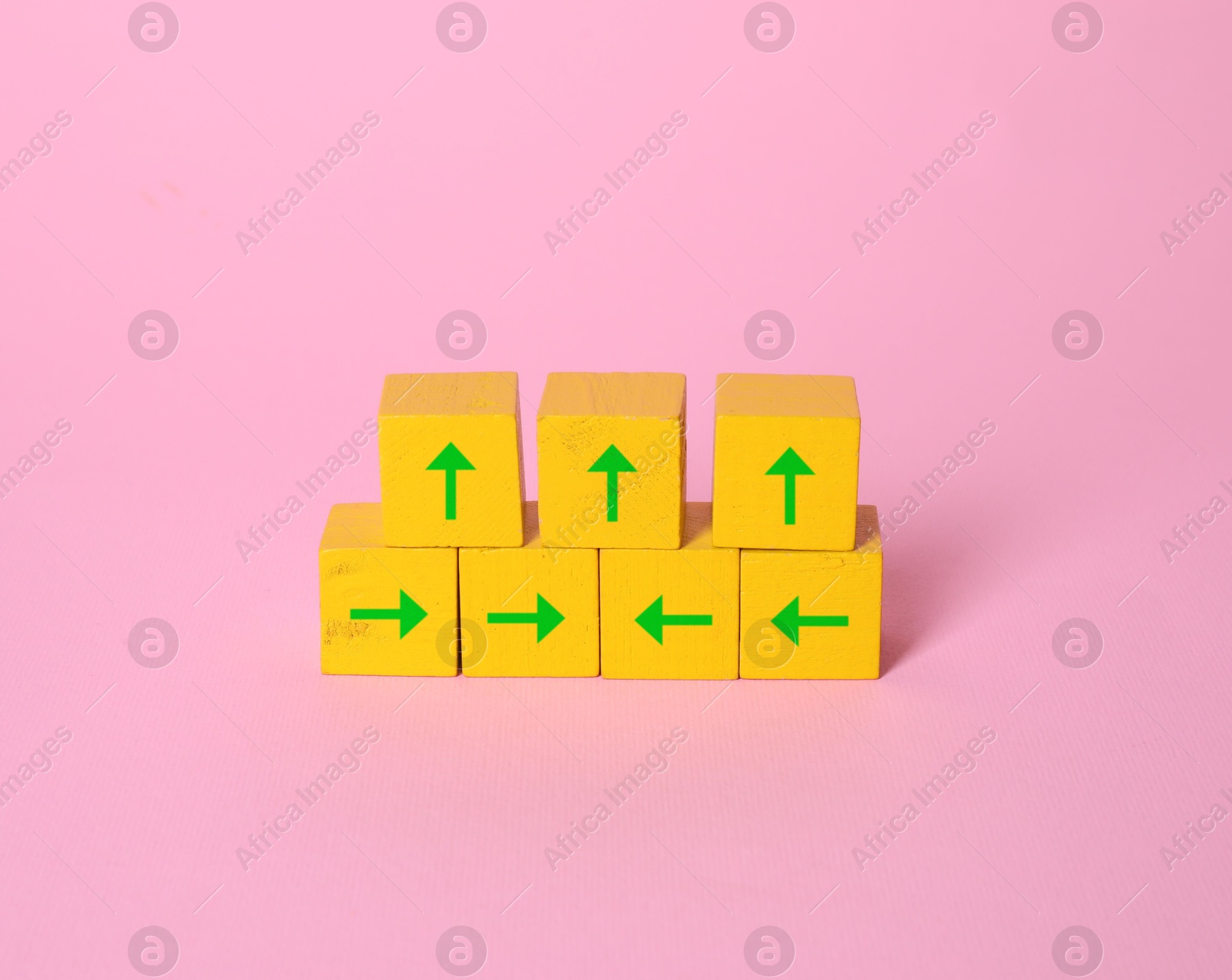 Image of Yellow cubes with green arrows on pink background