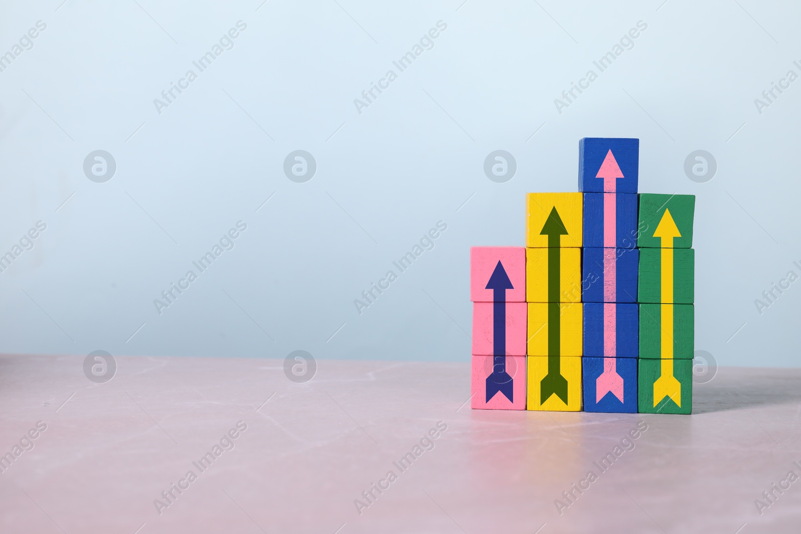 Image of Arrows made on colorful cubes on marble table, space for text