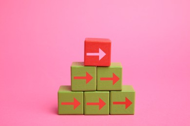 Image of Cubes with arrows and red one on top against pink background