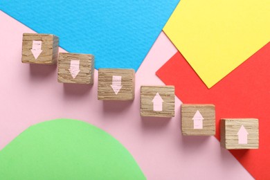 Image of Wooden cubes with pink arrows on colorful background, top view