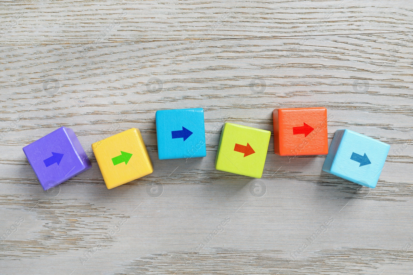 Image of Colorful cubes with arrows on wooden background, top view