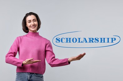 Image of Scholarship. Happy student pointing at word on light grey background