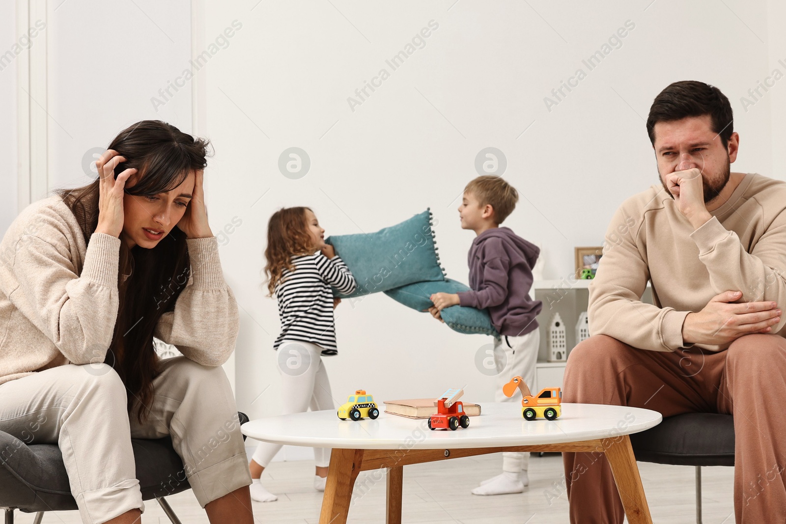 Photo of Overwhelmed parents and their naughty children at home