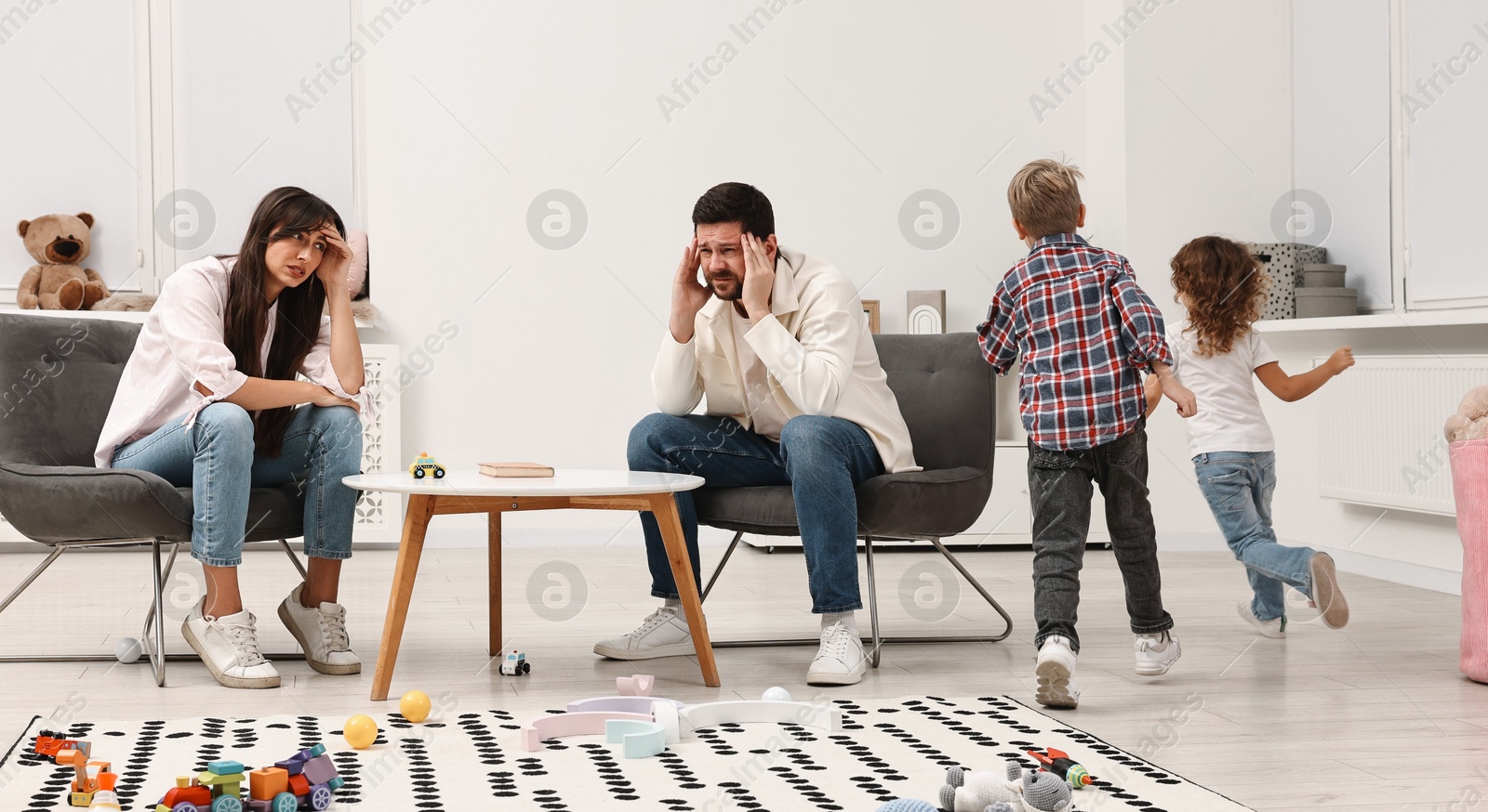 Photo of Hyperactive children playing and their overwhelmed parents at home