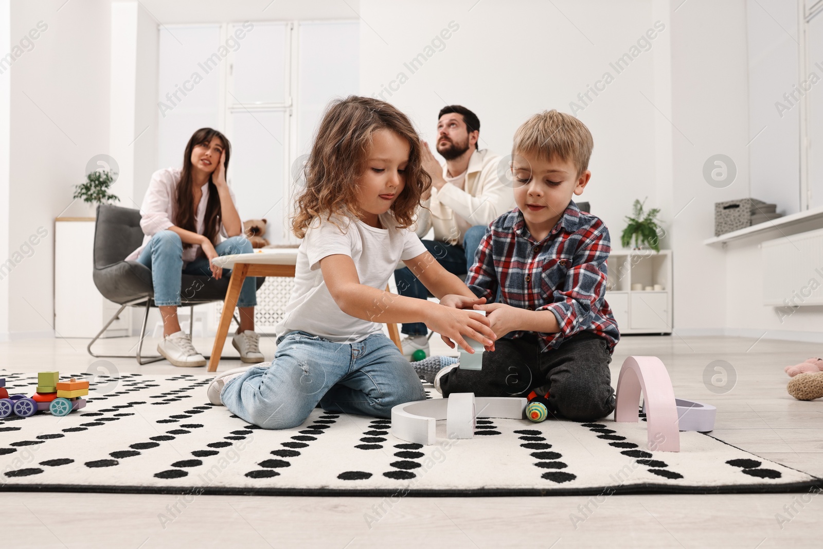 Photo of Hyperactive children playing and their overwhelmed parents at home, low angle view