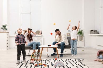 Photo of Hyperactive children playing and their overwhelmed parents at home