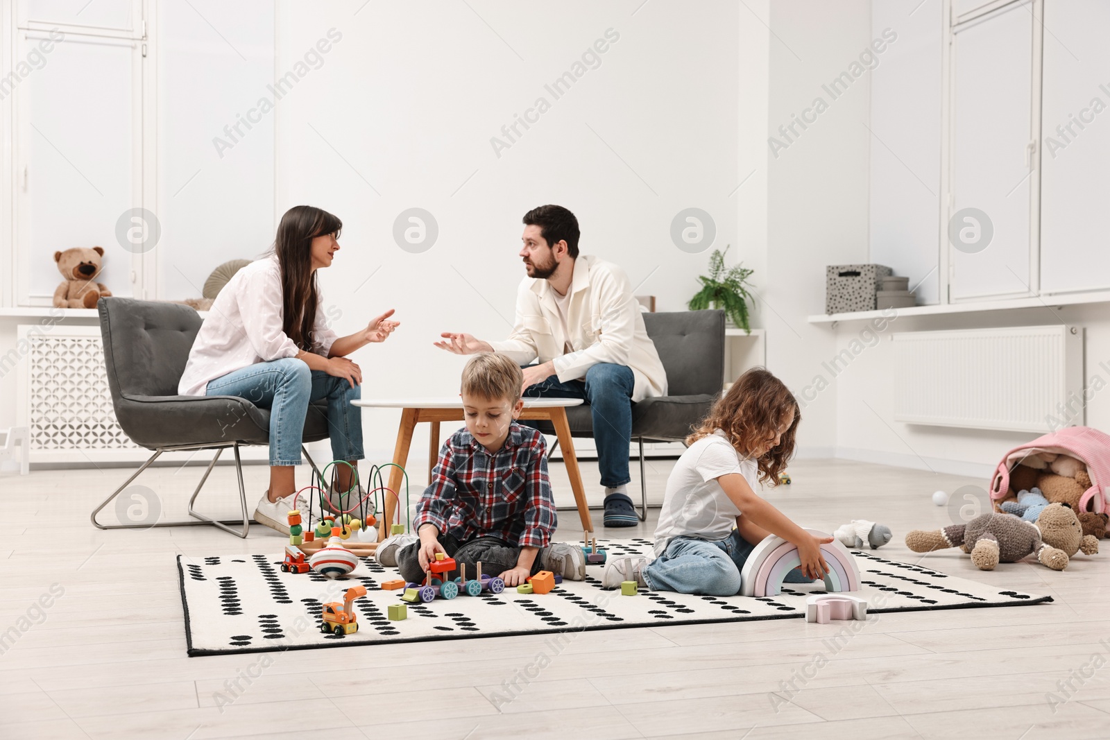 Photo of Hyperactive children playing while their overwhelmed parents talking at home