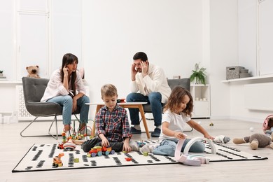 Hyperactive children playing and their overwhelmed parents at home