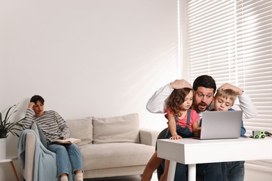 Photo of Father with children using laptop while their overwhelmed mother on sofa at home. Space for text