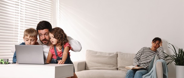 Photo of Father with children using laptop while their overwhelmed mother on sofa at home. Space for text