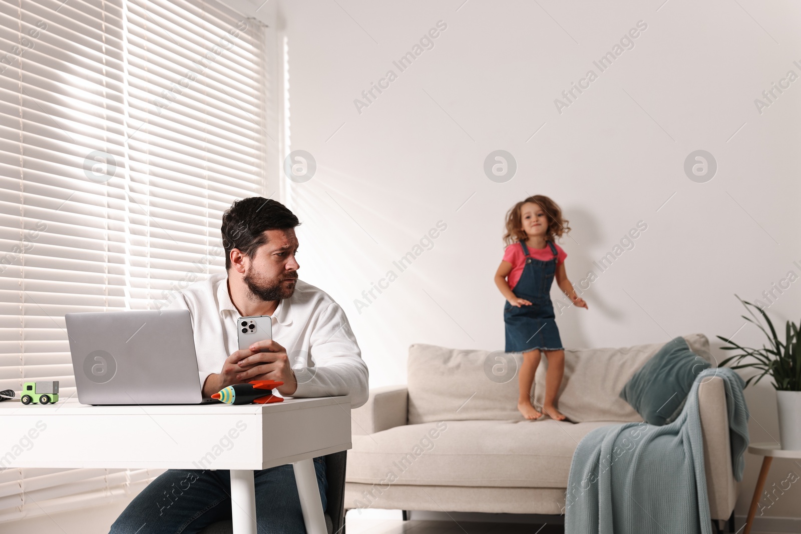 Photo of Naughty daughter disturbing her overwhelmed father at home