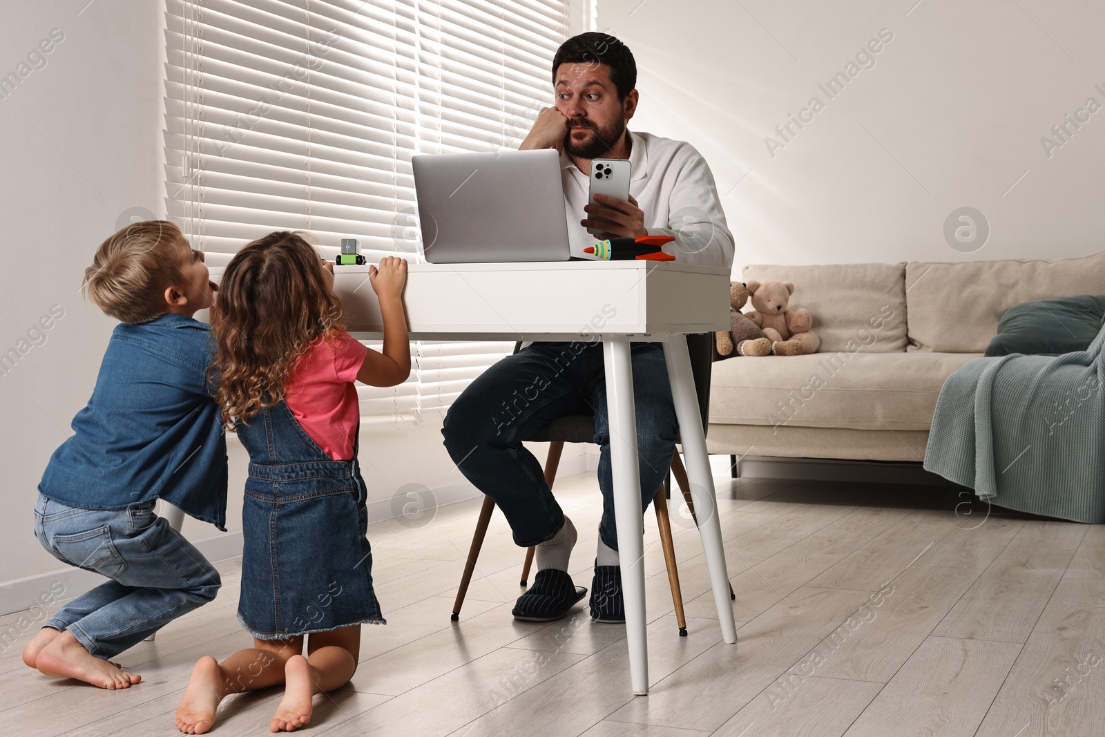 Photo of Naughty children disturbing their overwhelmed father at home