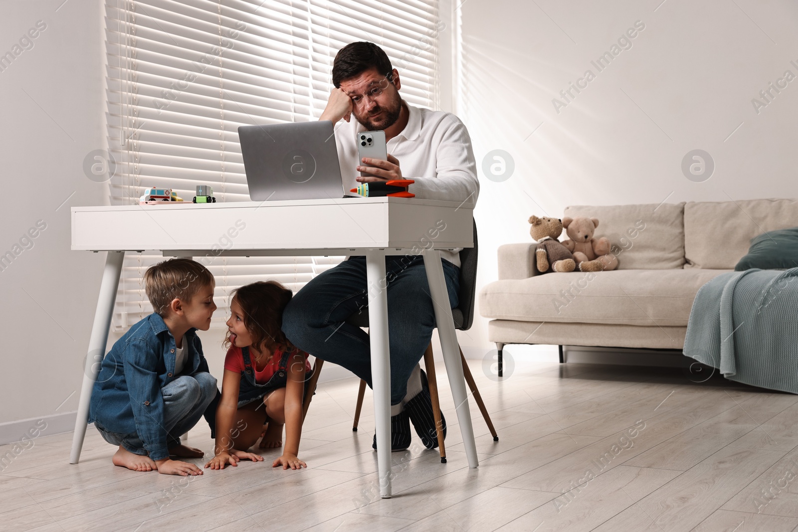 Photo of Naughty children disturbing their overwhelmed father at home