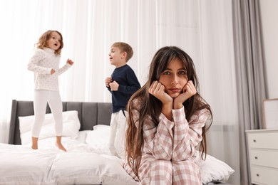 Photo of Overwhelmed mother and her playful children on bed at home, selective focus