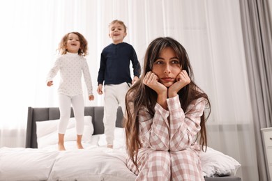 Photo of Overwhelmed mother and her playful children on bed at home, selective focus