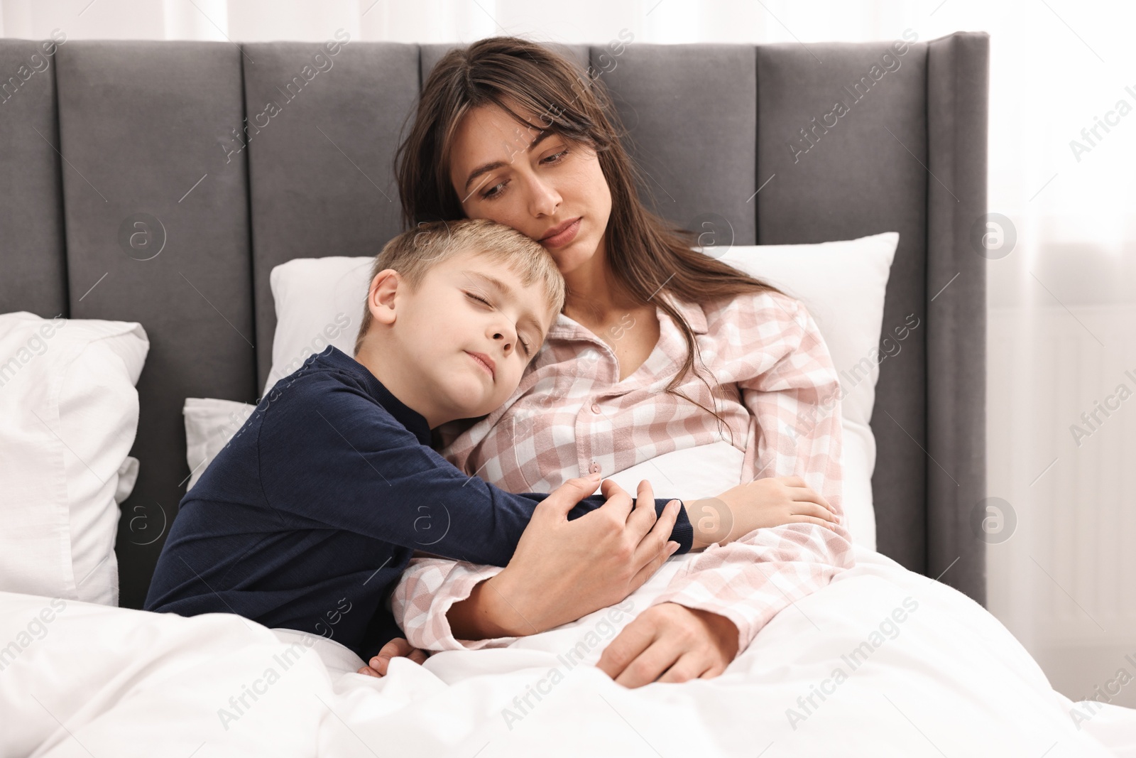 Photo of Overwhelmed mother with her son in bed at home