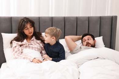 Photo of Overwhelmed parents and their son in bed at home