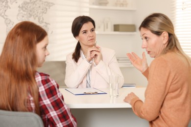 Photo of Difficult teenager. Mother and daughter having consultation with psychologist in office, selective focus