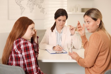 Photo of Difficult teenager. Mother and daughter having consultation with psychologist in office, selective focus