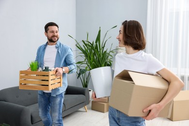 Photo of Moving day. Happy couple with boxes in their new home, selective focus