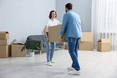 Moving day. Happy couple carrying box in their new home