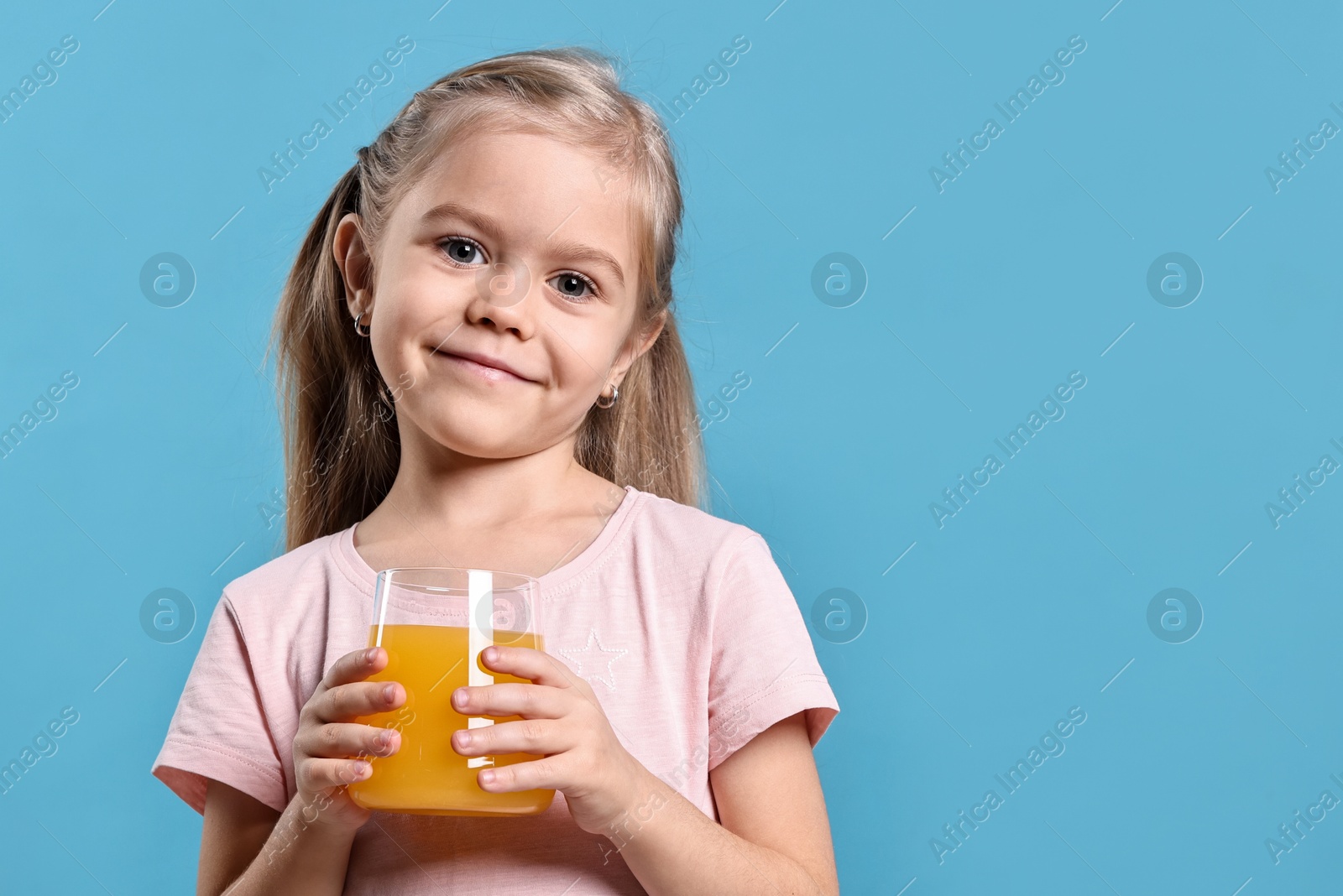 Photo of Girl with glass of orange juice on light blue background. Refreshing drink