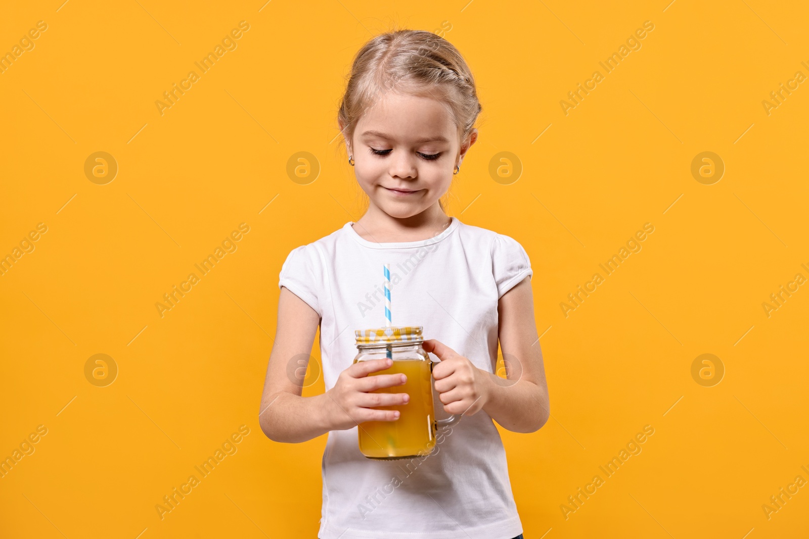 Photo of Girl with mason jar of juice on orange background. Refreshing drink