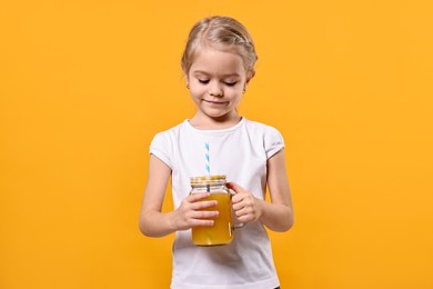 Photo of Girl with mason jar of juice on orange background. Refreshing drink