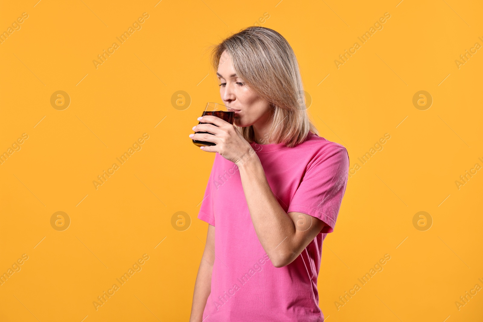 Photo of Woman with glass of refreshing soda drink on orange background, space for text