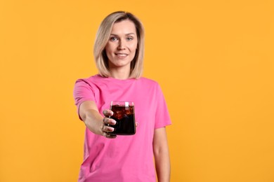 Photo of Woman with glass of refreshing soda drink on orange background