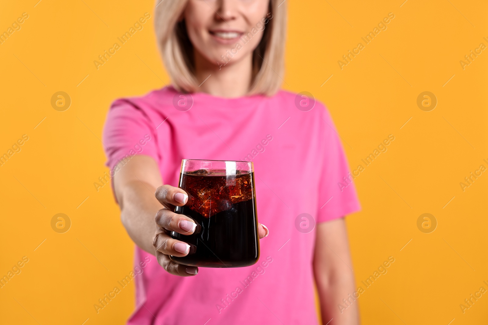 Photo of Woman with glass of refreshing soda drink on orange background, closeup