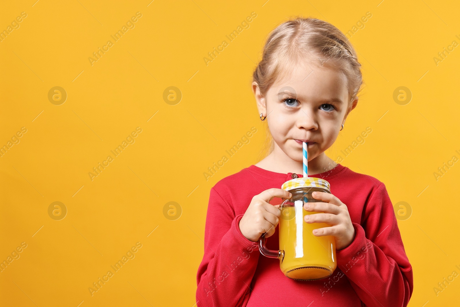 Photo of Girl drinking tasty juice on orange background, space for text. Refreshing drink