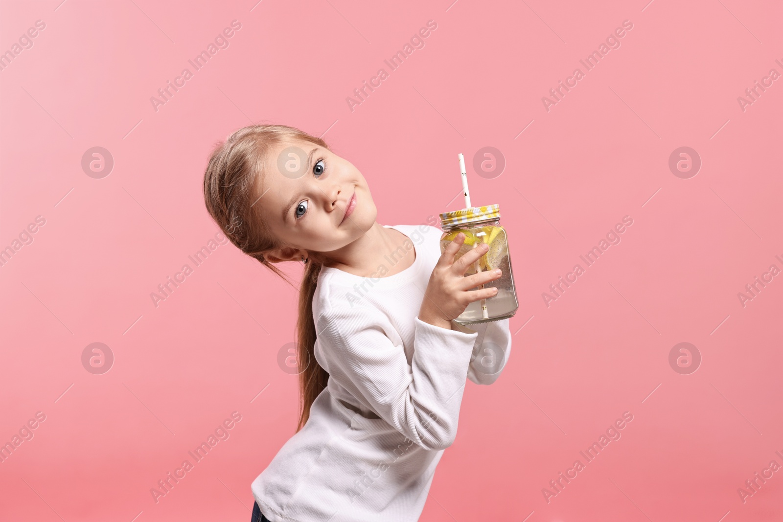 Photo of Girl with mason jar of lemonade on pink background. Refreshing drink