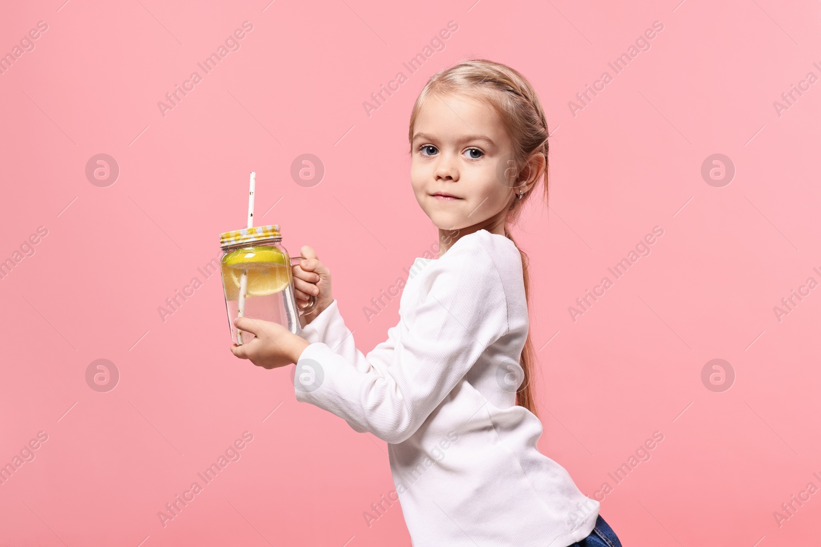 Photo of Girl with mason jar of lemonade on pink background. Refreshing drink