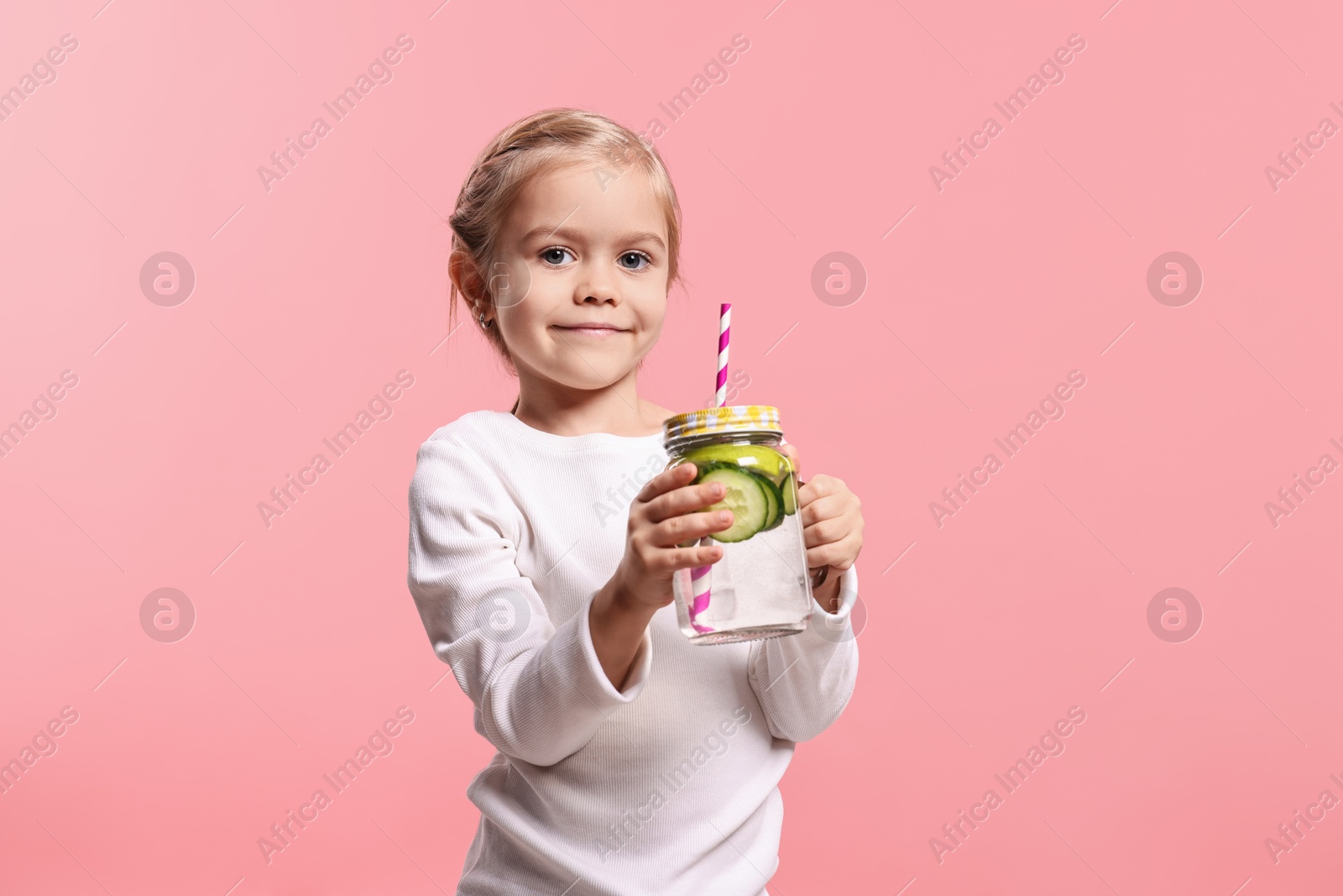 Photo of Girl with mason jar of cucumber water on pink background. Refreshing drink