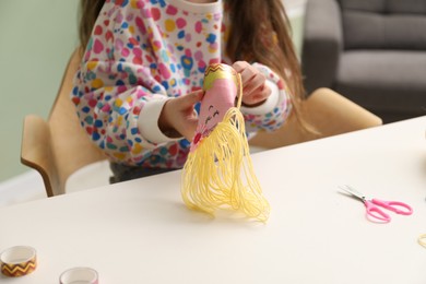 Photo of Little girl making craft at white table indoors, closeup. Child creativity