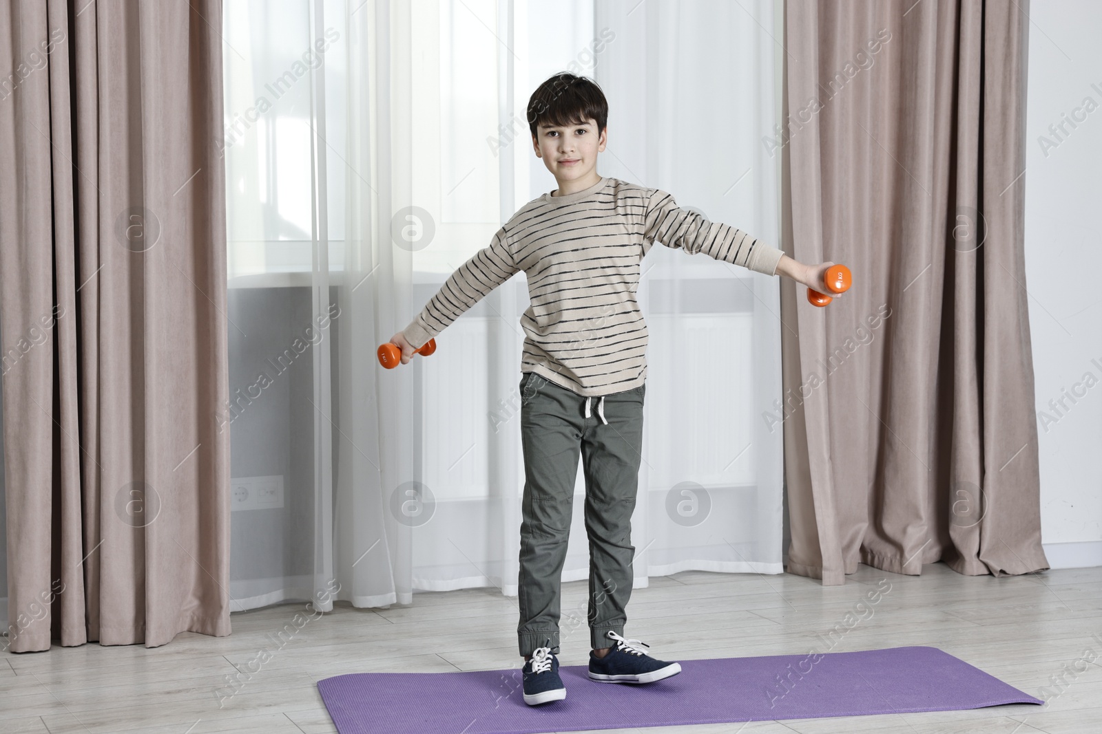 Photo of Little boy exercising with dumbbells at home. Morning routine