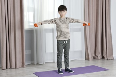 Photo of Little boy exercising with dumbbells at home. Morning routine