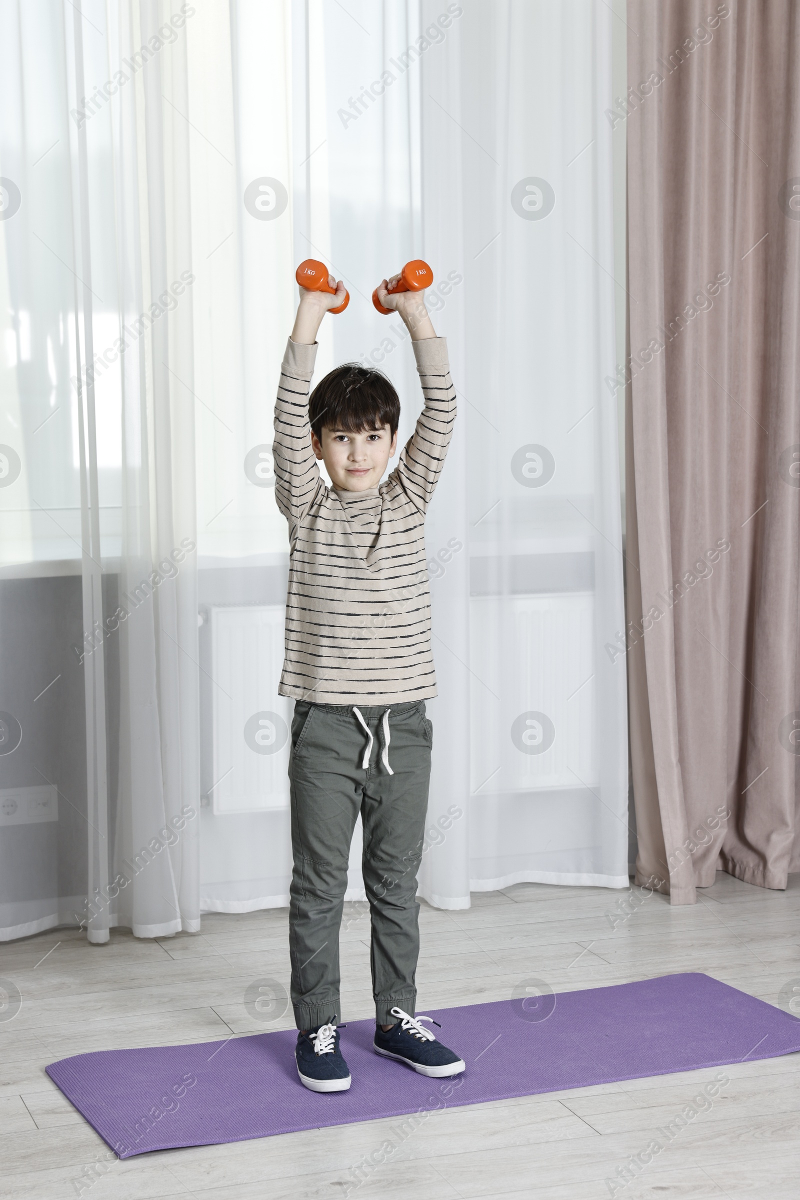 Photo of Little boy exercising with dumbbells at home. Morning routine